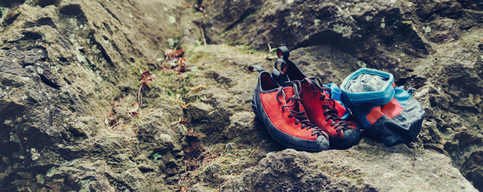 Climbing shoes and chalk bag with magnesium powder on stone rock outdoor fb